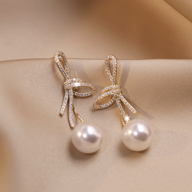 Elegant gold pearl earrings with sparkling bow